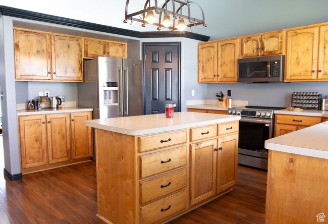 Kitchen with stainless steel appliances, wood floors, light countertops, and a center island | Image 9