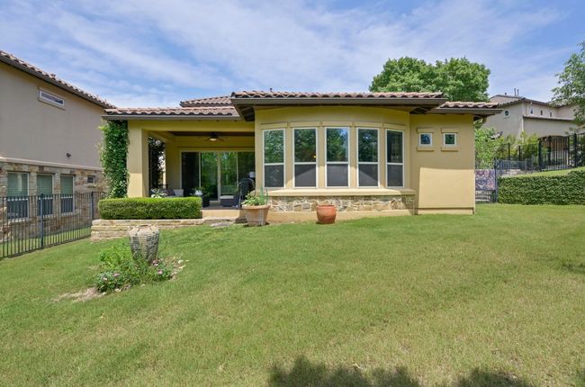 Rear view of property featuring a tiled roof, stucco siding, and stone accents | Image 21