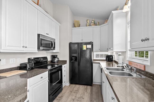 Kitchen with a peninsula, wood finished floors, visible vents, and black appliances | Image 23
