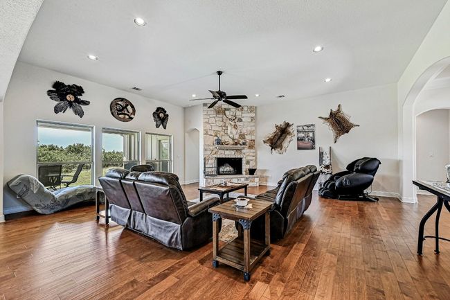 Living room with arched walkways, a fireplace, wood-type flooring, a ceiling fan, and recessed lighting | Image 7