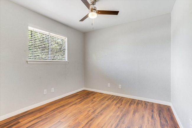 Empty room with ceiling fan, baseboards, and wood finished floors | Image 10