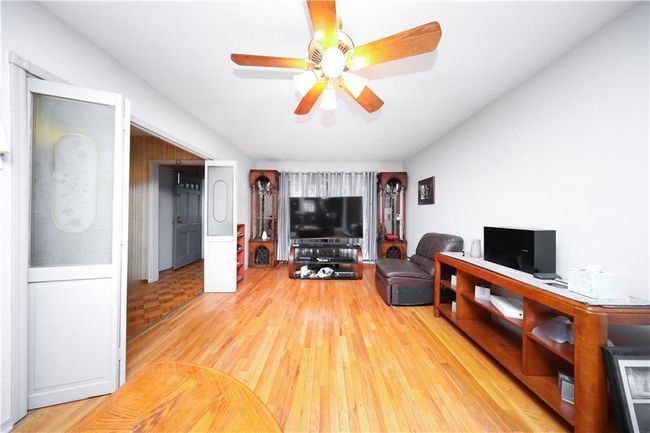 Living area with wood finished floors and a ceiling fan | Image 5