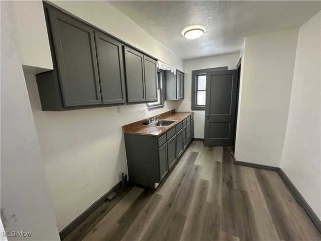 Kitchen featuring dark countertops, wood finished floors, a textured ceiling, and baseboards | Image 29