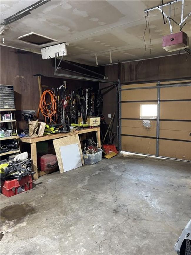 Oversized 2 Car attached Garage featuring electric garage door, shelving and a work bench | Image 26