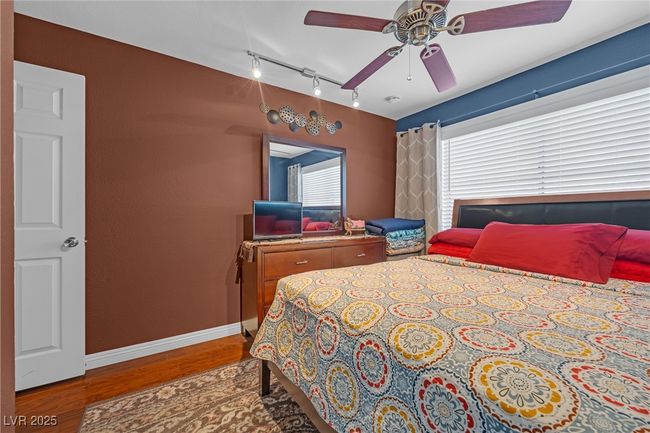 Bedroom featuring a ceiling fan, track lighting, baseboards, and wood finished floors | Image 20