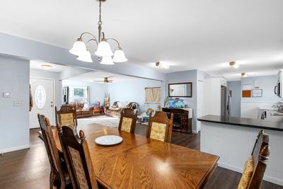 Dining room featuring dark hardwood / wood-style flooring, ceiling fan with notable chandelier, and washer / dryer | Image 3