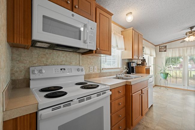 Kitchen with white appliances, a sink, lofted ceiling, a textured ceiling, and healthy amount of natural light | Image 10
