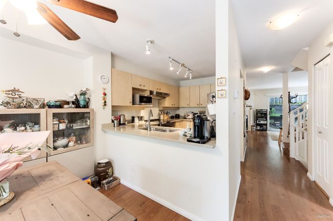 Kitchen featuring a sink, ceiling fan, wood finished floors, stainless steel microwave, and light brown cabinetry | Image 6