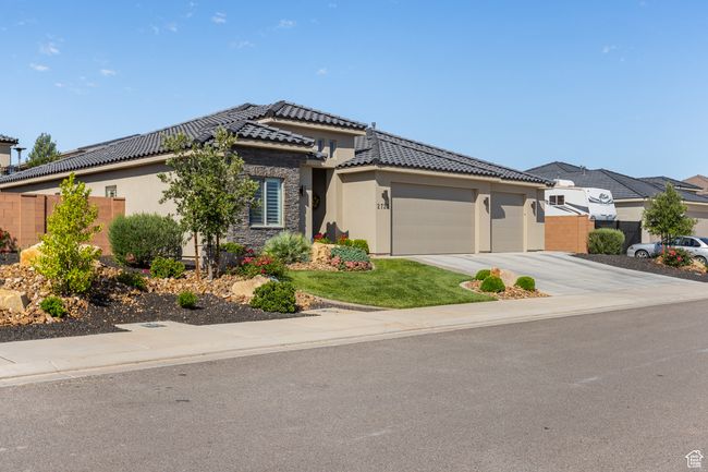 Prairie-style house featuring an attached garage, stucco siding, a tile roof, driveway, and stone siding | Image 60