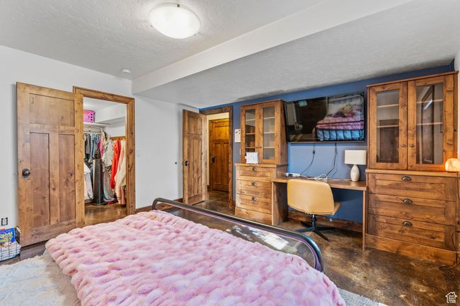 Bedroom with a spacious closet, built in desk, a textured ceiling, and a closet | Image 44