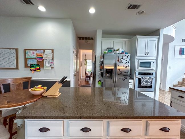 Kitchen with stainless steel appliances, white cabinets, a kitchen island, dark stone countertops, and recessed lighting | Image 14