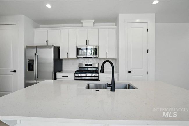 Kitchen with stainless steel appliances, white cabinets, recessed lighting, tasteful backsplash, and light stone counters | Image 9