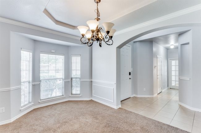 Spare room with arched walkways, a chandelier, light carpet, crown molding, and light tile patterned floors | Image 6
