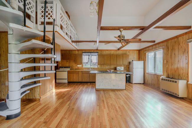 Kitchen with wood walls, white appliances, a healthy amount of sunlight, and light wood-type flooring | Image 14