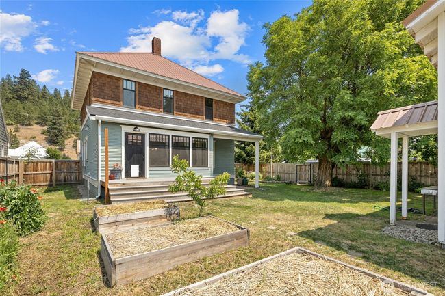 The backyard with raised garden beds and large Locust tree creates an outdoor retreat. | Image 30