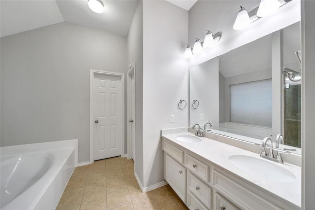 The luxurious en'suite bath is nicely updated with double sinks, a quartz vanity, and center drawer storage. | Image 18