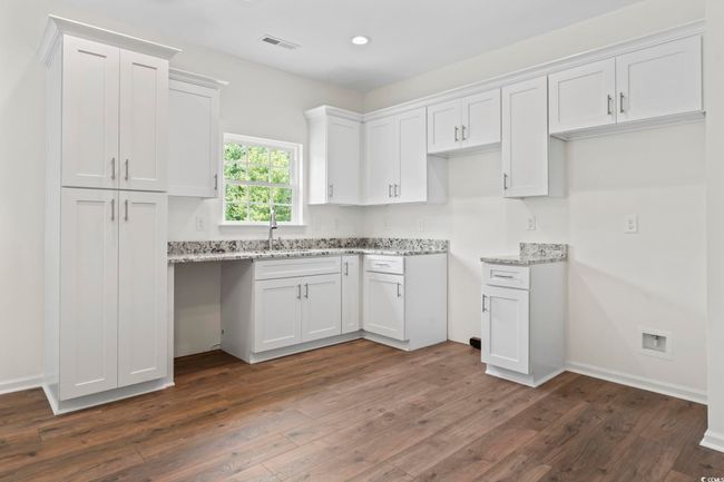 Kitchen featuring light stone countertops, dark wood-type flooring, white cabinets, recessed lighting, and a sink | Image 8