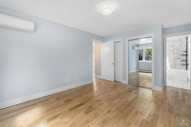 Unfurnished bedroom featuring a wall mounted air conditioner, light wood-style floors, multiple closets, baseboards, and connected bathroom | Image 25