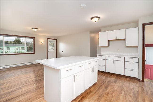 Kitchen featuring light countertops, a baseboard radiator, white cabinets, and light wood-type flooring | Image 11