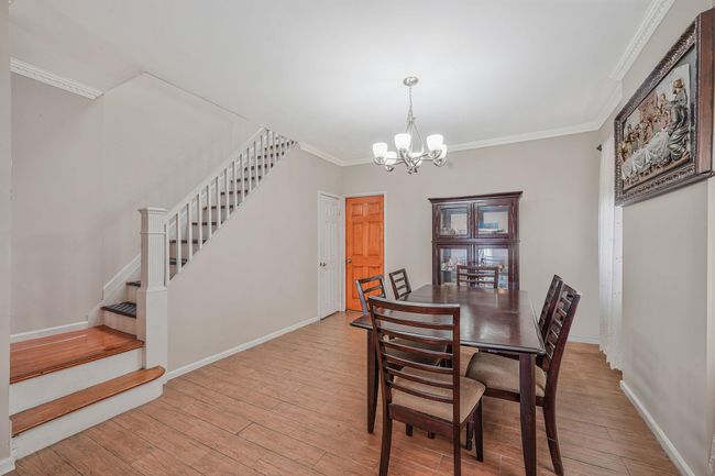 Dining area with a chandelier, stairway, crown molding, wood finished floors, and baseboards | Image 9