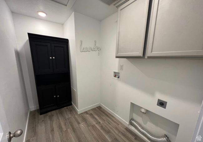 Washroom featuring electric dryer hookup, cabinet space, wood finished floors, and washer hookup | Image 12