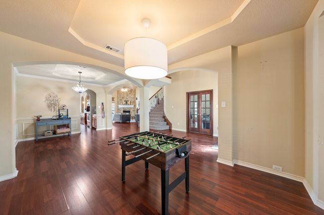 Game room with a tray ceiling, wood finished floors, arched walkways, and visible vents | Image 15