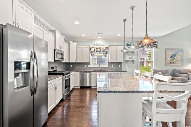Kitchen featuring stainless steel appliances, plenty of natural light, a kitchen island, a breakfast bar area, and crown molding | Image 12