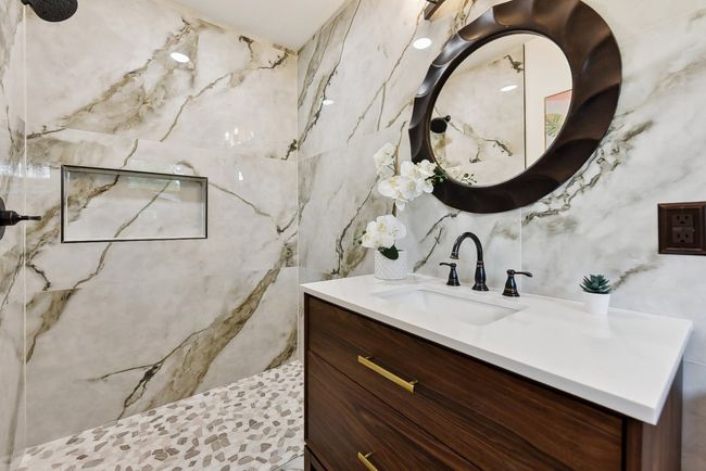 Bathroom with tile walls, vanity, and a tile shower | Image 5