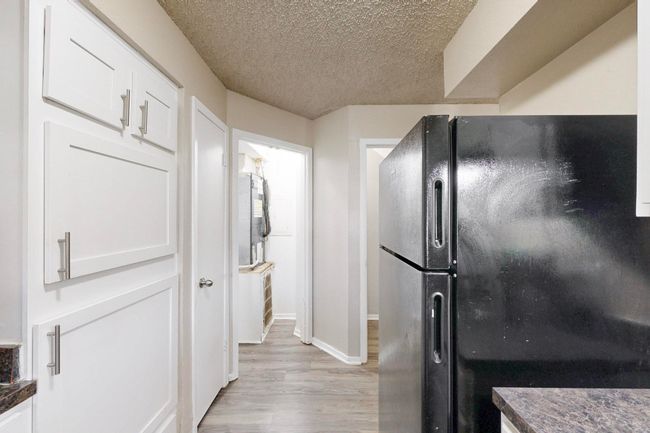 Kitchen with dark countertops, a textured ceiling, white cabinetry, and freestanding refrigerator | Image 23