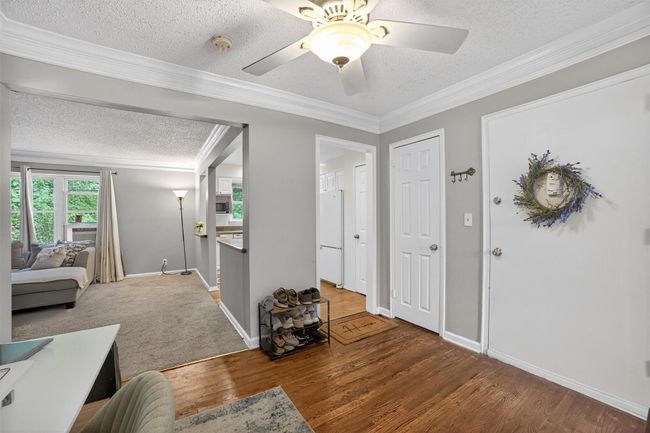 Foyer entrance featuring a textured ceiling, wood finished floors, ornamental molding, and a ceiling fan | Image 5
