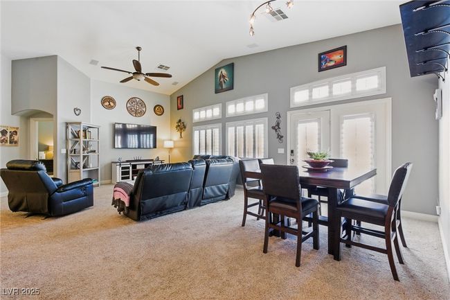 Dining room with high vaulted ceiling, ceiling fan, arched walkways, carpet flooring, and visible vents | Image 13