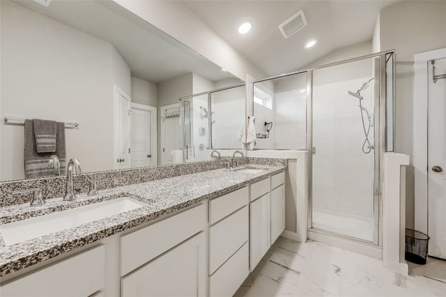 Bathroom featuring a stall shower, double vanity, recessed lighting, and marble look tiles | Image 21