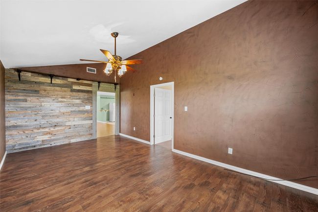 Unfurnished room featuring vaulted ceiling, wood finished floors, ceiling fan, and wood walls | Image 14