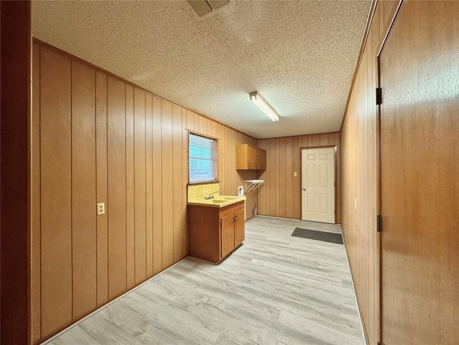 Kitchen featuring sink, light hardwood / wood-style floors, a textured ceiling, and wood walls | Image 27