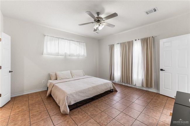 Bedroom with light tile patterned floors and ceiling fan | Image 12