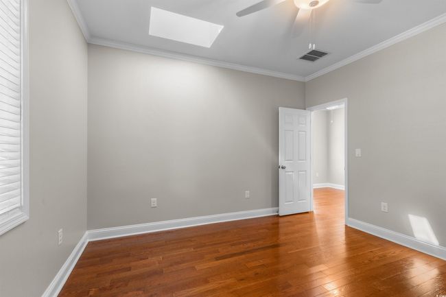 Spare room featuring a skylight, ceiling fan, hardwood / wood-style flooring, crown molding, and baseboards | Image 18
