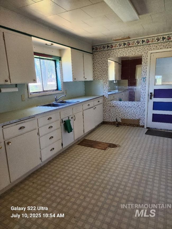 Kitchen featuring light countertops, white cabinetry, and wallpapered walls | Image 26