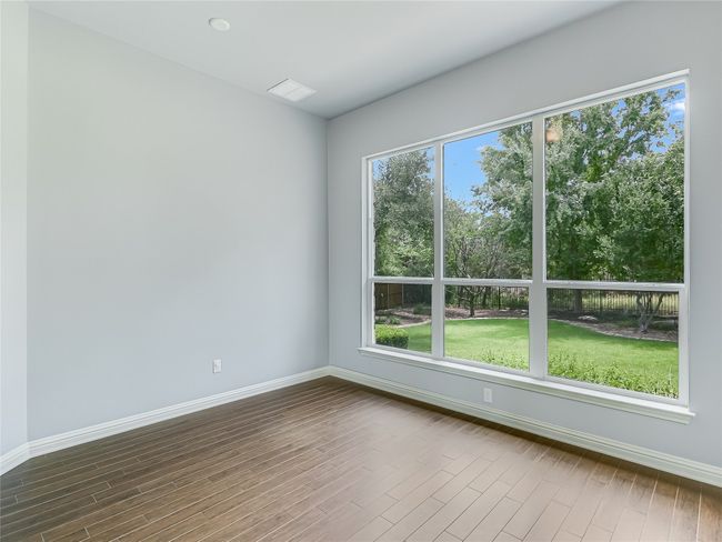 The sun room flex space off the living area brings in natural light to the home and offers relaxing serene views of the beautiful backyard and wooded green space. | Image 12