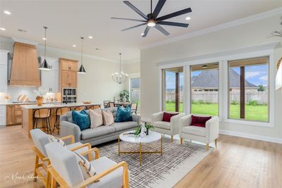 Living room with light hardwood / wood-style floors, ceiling fan with notable chandelier, and crown molding | Image 3