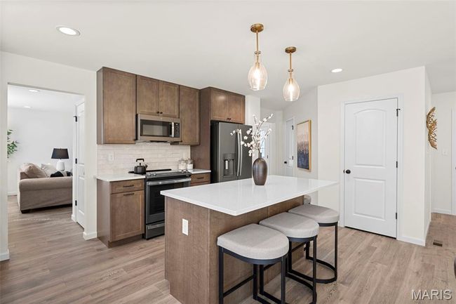 Kitchen with stainless steel appliances, light wood-type flooring, a kitchen breakfast bar, light countertops, and recessed lighting | Image 9