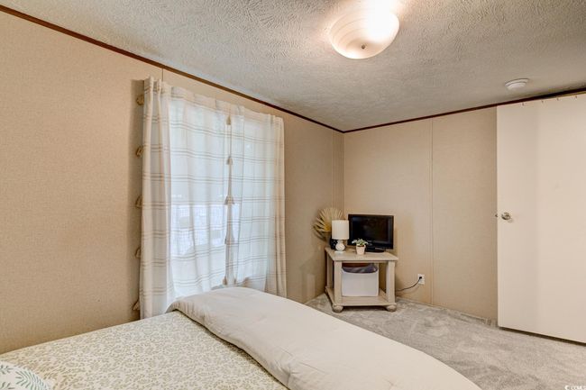 Carpeted bedroom with crown molding and a textured ceiling | Image 25