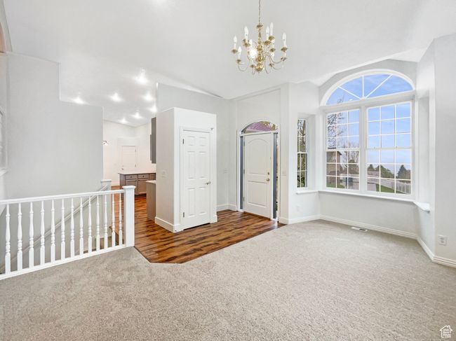 Carpeted empty room with visible vents, vaulted ceiling, baseboards, and an inviting chandelier | Image 11