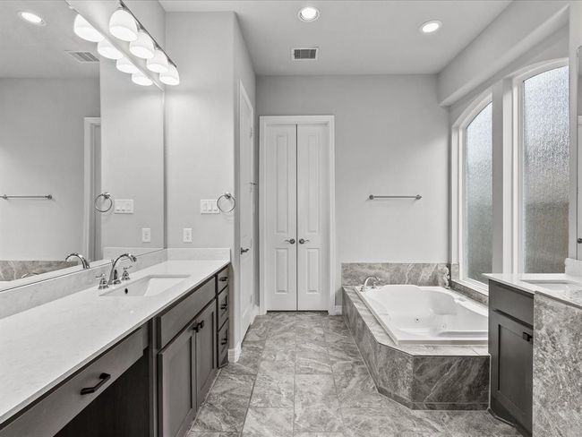 The primary en-suite bath features dual vanities, a soaking tub, walk-in shower and a large walk-in closet | Image 20