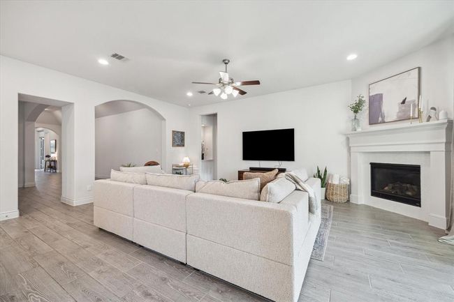 A gentle archway invites you from the entry into the expansive living room, where ample space for a large, cozy couch surrounds a striking fireplace, the heart of this warm and inviting gathering area. | Image 15