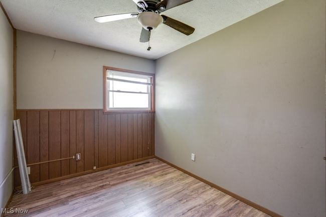 Spare room with wood finished floors, wainscoting, a textured ceiling, a ceiling fan, and wooden walls | Image 19