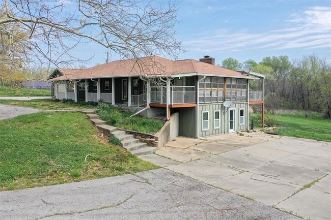 View of front of property featuring board and batten siding, a chimney, a sunroom, and a front yard | Image 29