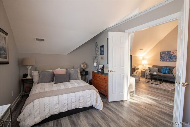 Bedroom with vaulted ceiling, wood finished floors, visible vents, and baseboards | Image 25