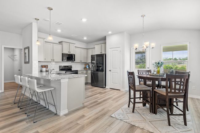 Kitchen featuring refrigerator with ice dispenser, range with electric stovetop, black microwave, a peninsula, and a breakfast bar | Image 15