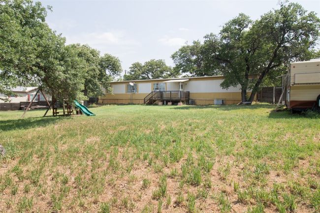 View of yard with a playground and a wooden deck | Image 18