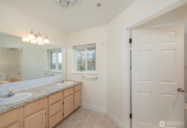 Double vanity ensuite, with soaking tub, shower, and toilet through doorway. | Image 25